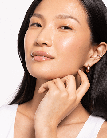 Riman ICD Beauty Glow Up Lip Oil - Close-up of a woman showcasing her radiant skin and earrings, exemplifying beauty and elegance.