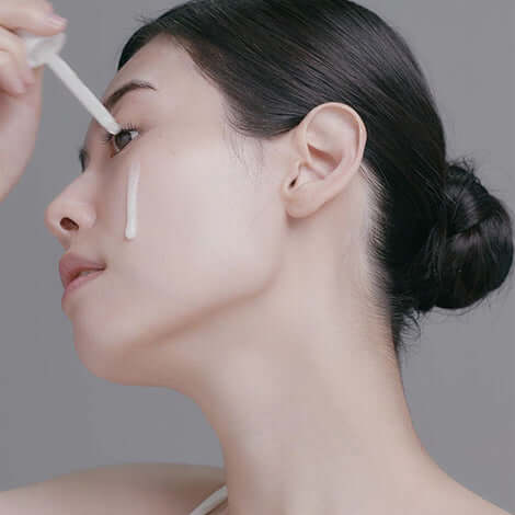 Woman applying RADIANSOME 100 Microfluidizer Ampoule to her face for hydration and anti-aging benefits.
