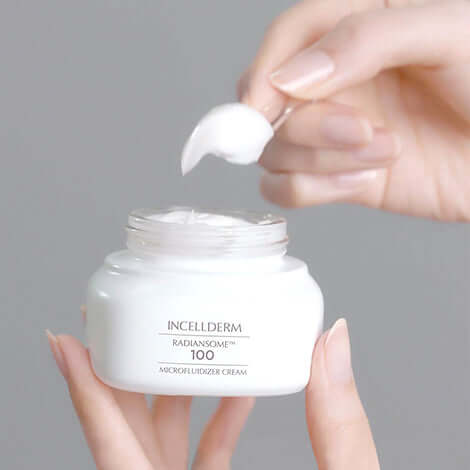 Hand holding a scoop of IncellDerm Radiansome 100 Microfluidizer Cream from the premium skincare bundle.