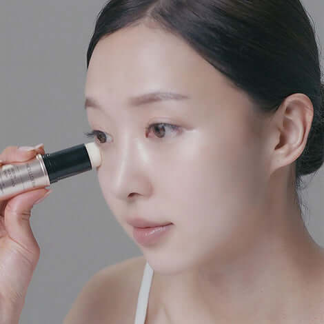 Woman applying Riman ICD Multi Stick Balm for instant hydration and youthful skin appearance.