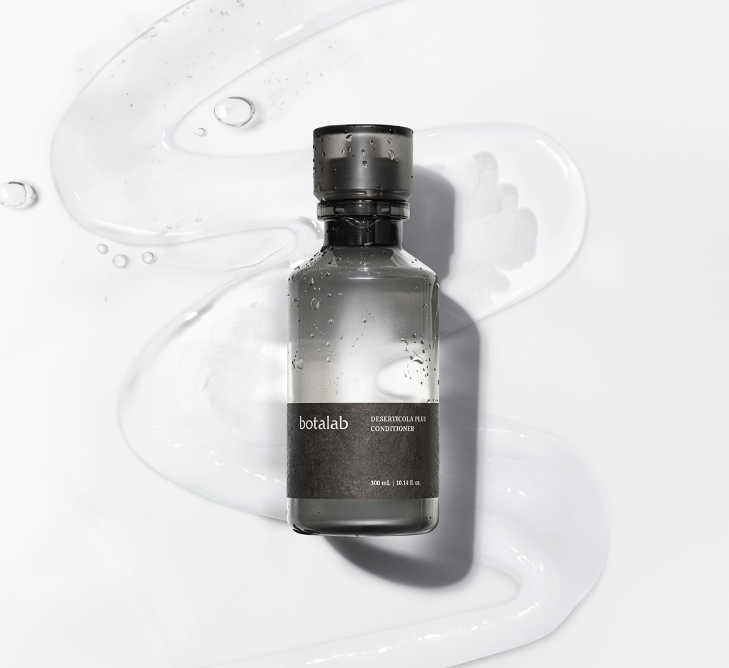 Riman Botalab Deserticola Plus Conditioner bottle on a wavy background with hydrating gel, perfect for hair care.