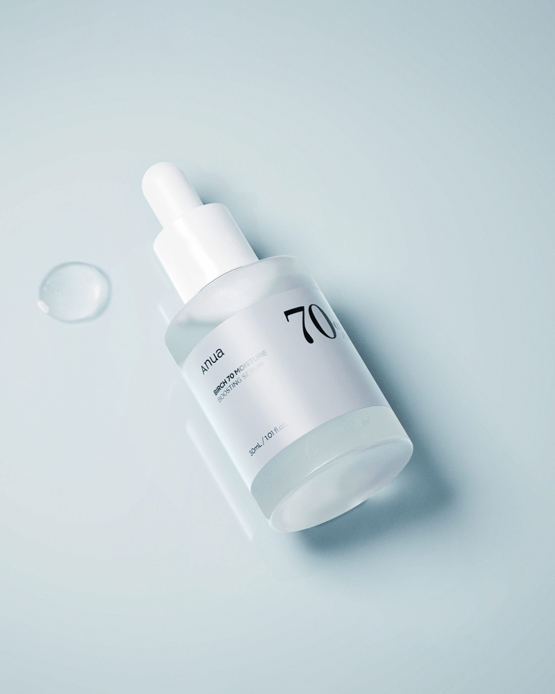 Anua Birch 70 Moisture Boosting Serum bottle with dropper on a reflective surface.