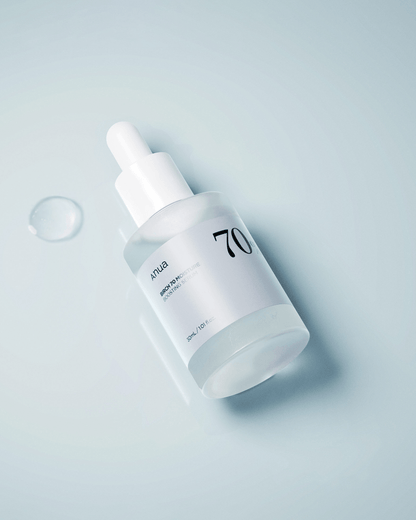 Anua Birch 70 Moisture Boosting Serum bottle with dropper on a reflective surface.