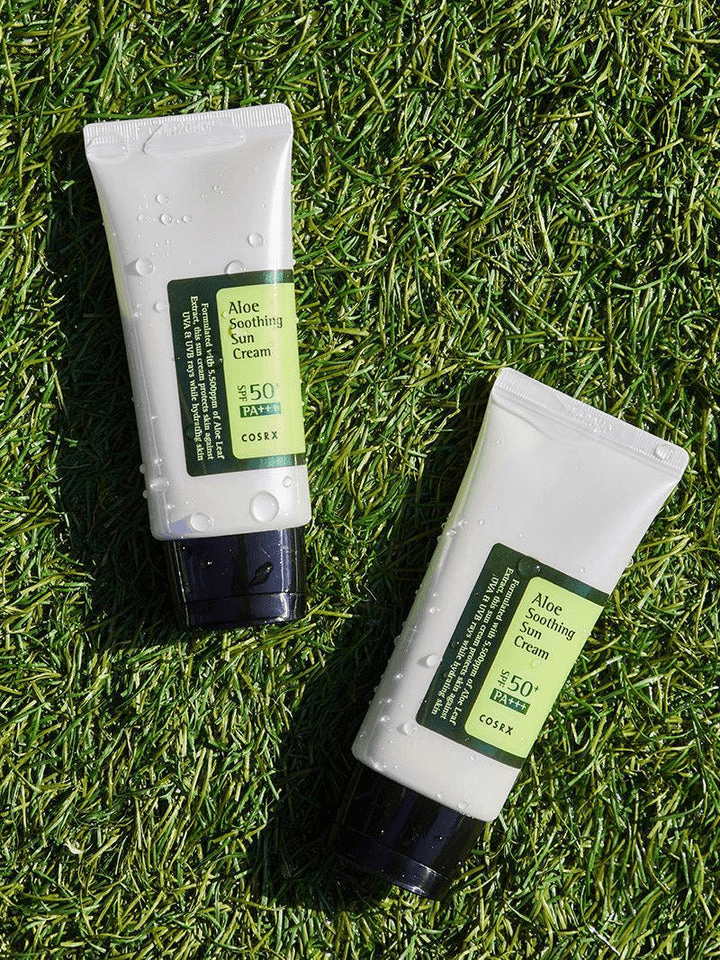 COSRX Aloe Soothing Sun Cream SPF50 tubes on green grass, ideal for Korean skincare and sun protection.