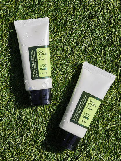 COSRX Aloe Soothing Sun Cream SPF50 tubes on green grass, ideal for Korean skincare and sun protection.