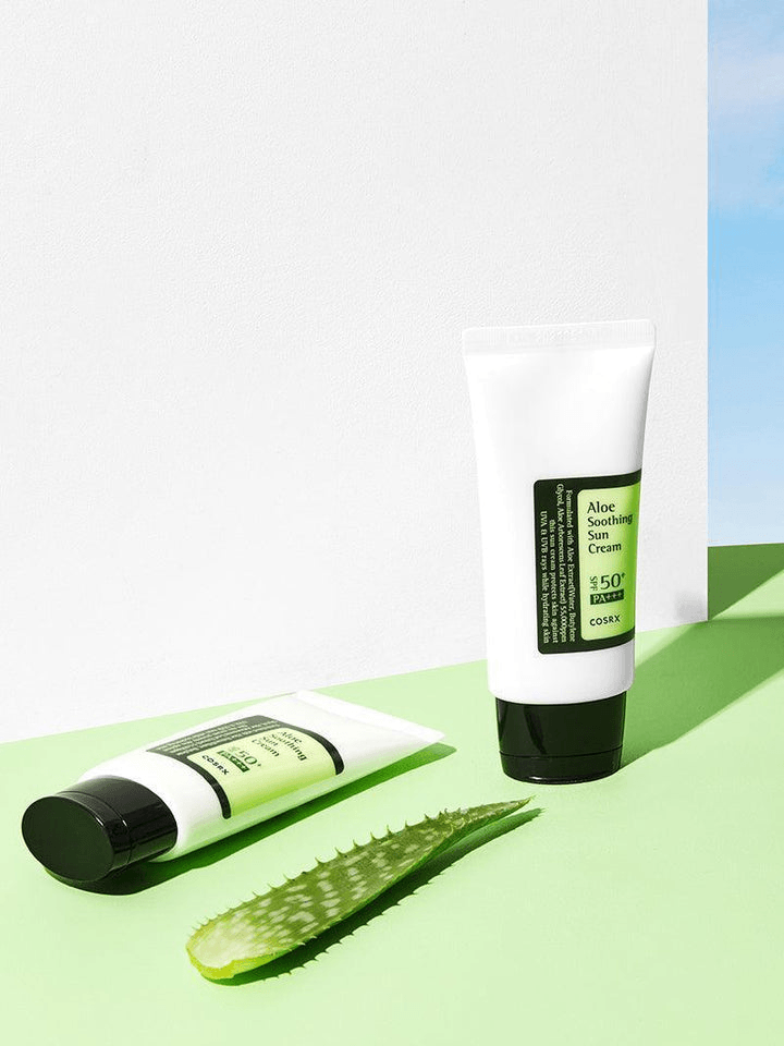 COSRX Aloe Soothing Sun Cream SPF50 with aloe vera leaf on green surface, perfect for Korean skincare.
