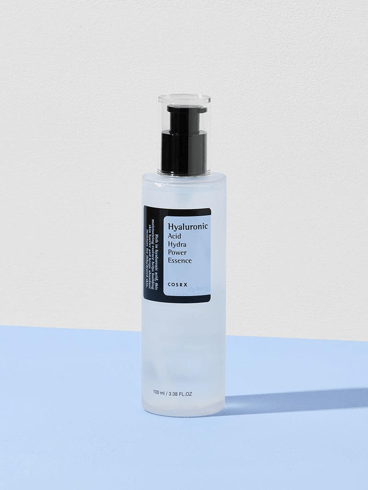 COSRX Hyaluronic Acid Hydra Power Essence in a clear bottle on a blue background.