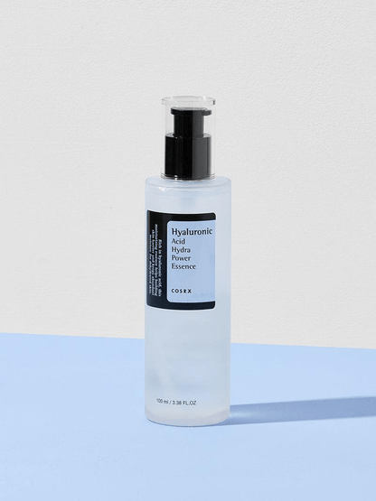 COSRX Hyaluronic Acid Hydra Power Essence in a clear bottle on a blue background.