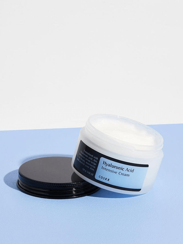 COSRX Hyaluronic Acid Intensive Cream jar on a blue background, showcasing its hydrating properties for supple skin.