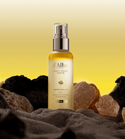 d'Alba White Truffle First Spray Serum bottle against a yellow and rocky background, emphasizing hydration and radiance.