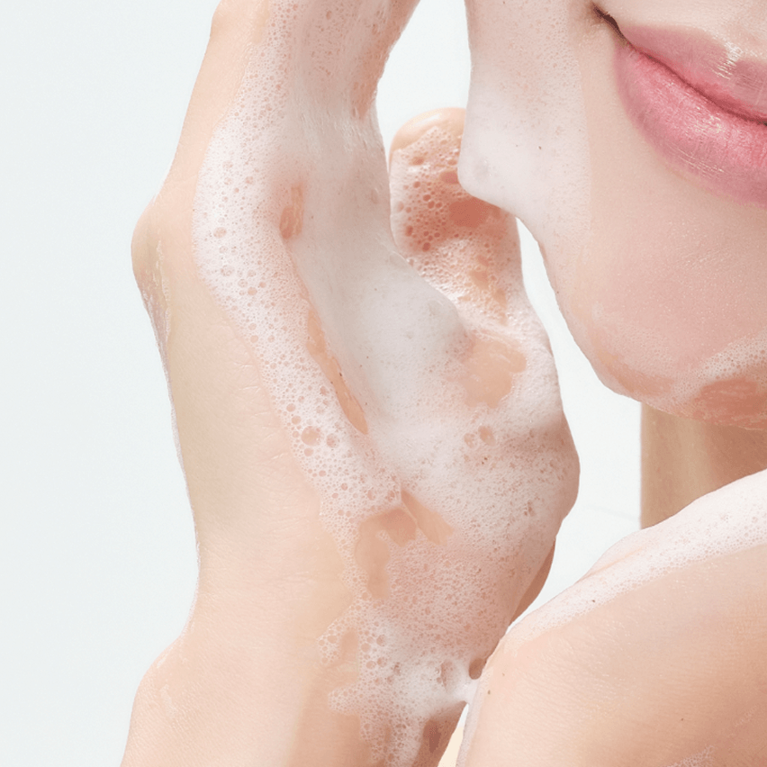 A close-up of a person cleansing their face with RIMAN ICD Balancing Gel Cleanser creating a gentle lather.