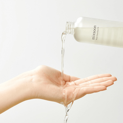 mixsoon Bean Cleansing Oil being poured into a hand, showcasing its lightweight texture for effective cleansing.