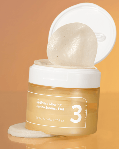 numbuzin No.3 Radiance Glowing Jumbo Essence Pads in a jar with a pad lifted, showcasing its essence-rich formula.